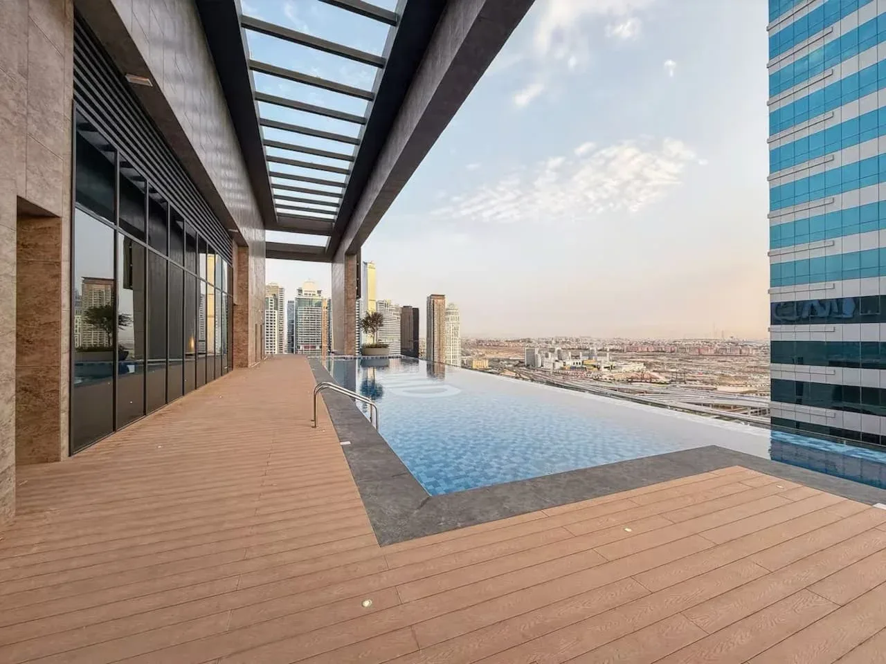 A rooftop pool sits beside a wooden deck overlooking the city skyline.
