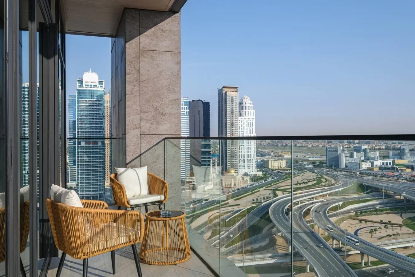 Un balcón con asientos tiene vistas a edificios de la ciudad y autopistas curvas.