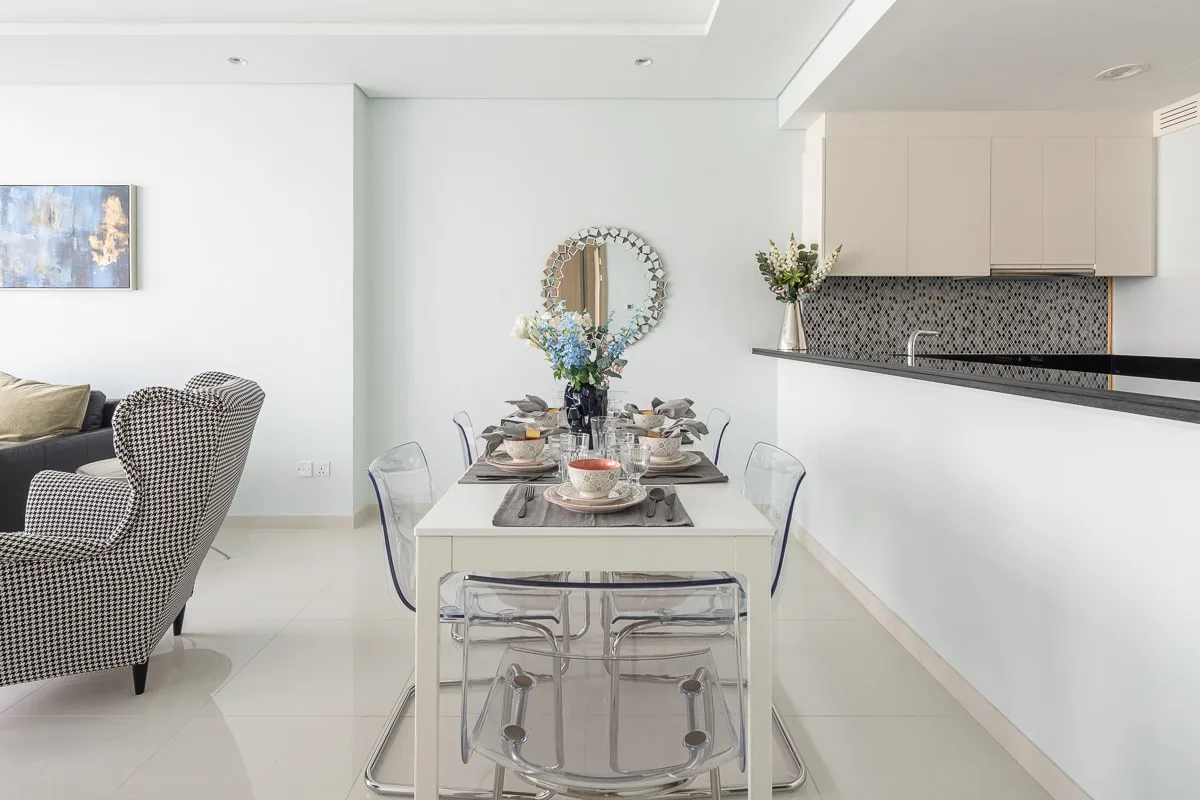 A dining area with a set table and an adjoining kitchen.