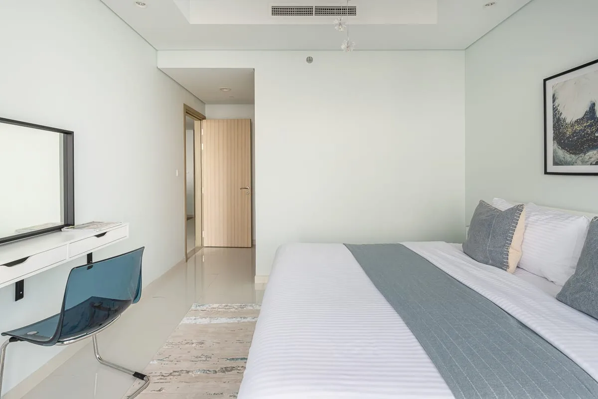 A bedroom with a bed, desk, and chair beside the doorway.
