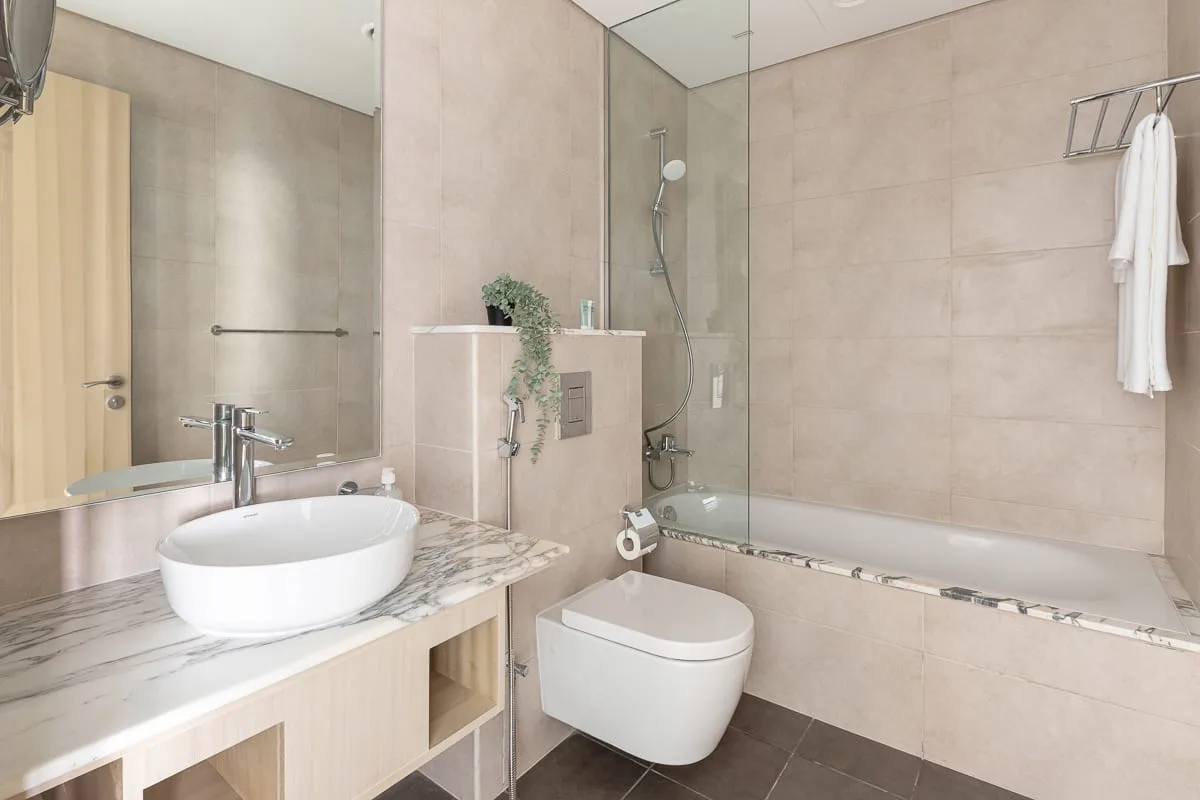 A tiled bathroom with a sink vanity and bathtub.
