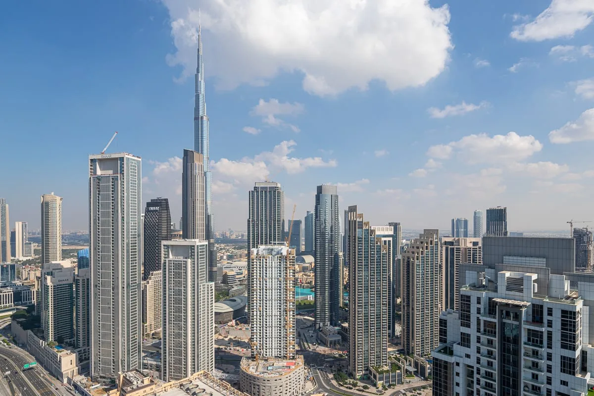 A city skyline with tall skyscrapers beneath a partly cloudy sky.