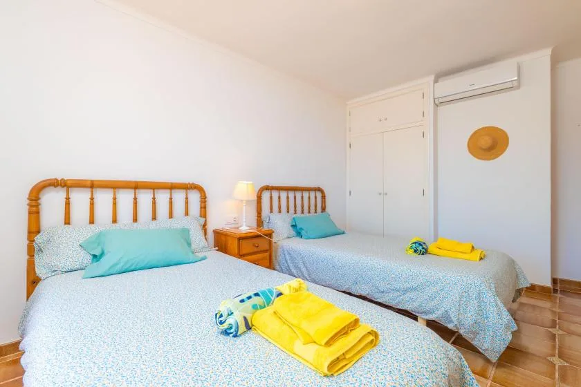 Un dormitorio luminoso con dos camas y toallas dobladas.