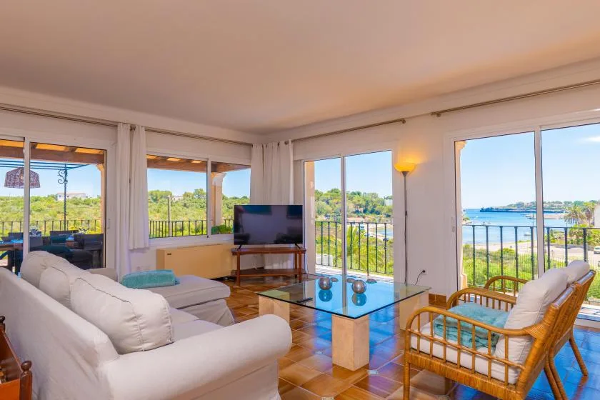 Una sala de estar luminosa con asientos, una mesa de centro de vidrio y vistas por grandes ventanales.
