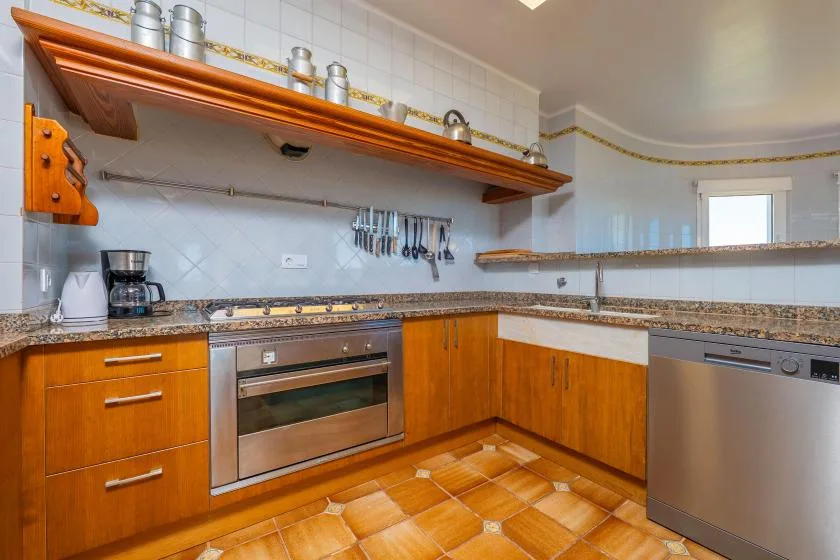 Una cocina con gabinetes de madera, un horno empotrado y suelo de baldosas.
