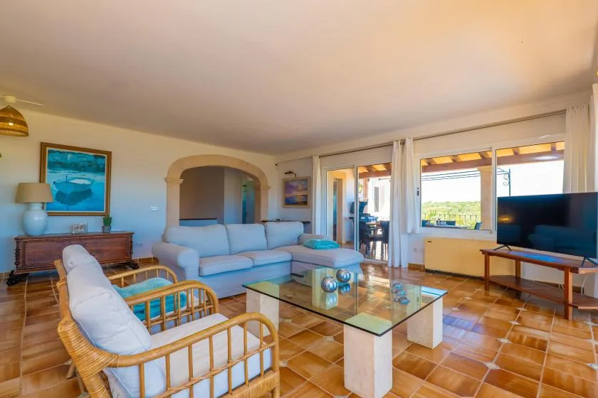 Una sala de estar con asientos, una mesa de centro de vidrio y ventanas grandes.