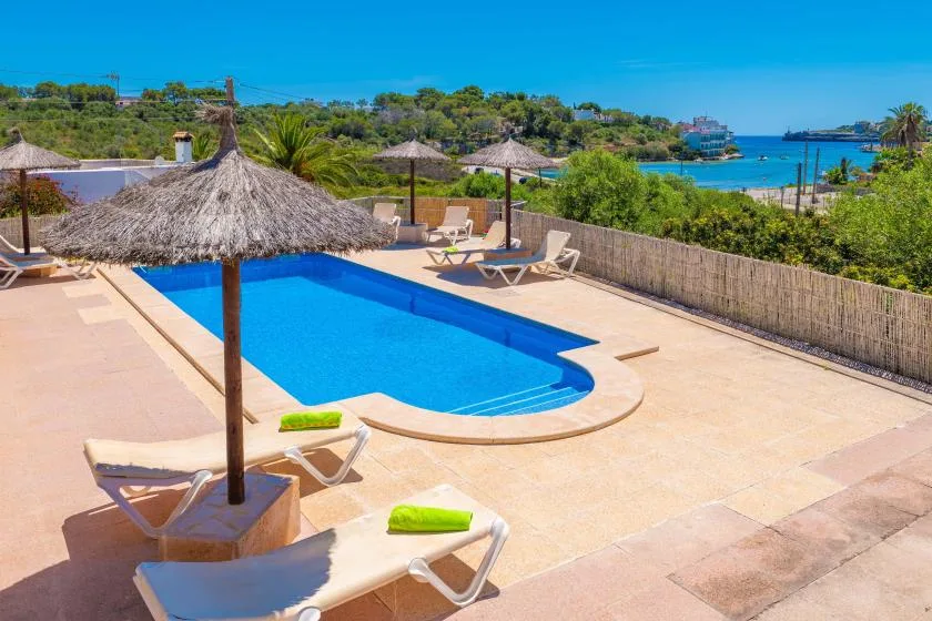 Una piscina al aire libre con tumbonas y el mar visible más allá de la terraza.