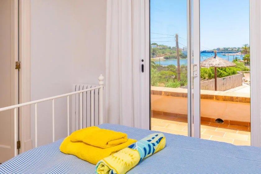 Un dormitorio con toallas dobladas sobre la cama y vistas a través de las puertas de cristal.