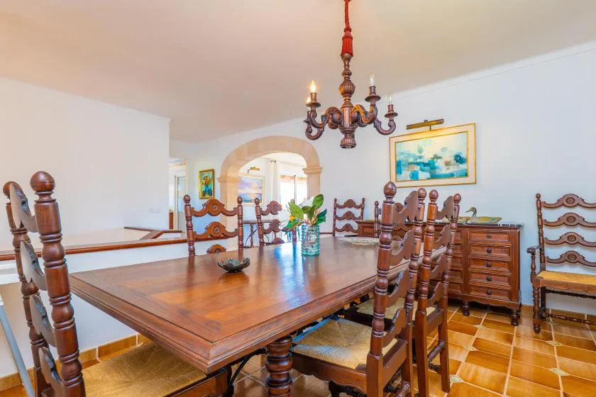 Un comedor con una gran mesa de madera y sillas bajo una lámpara de araña.
