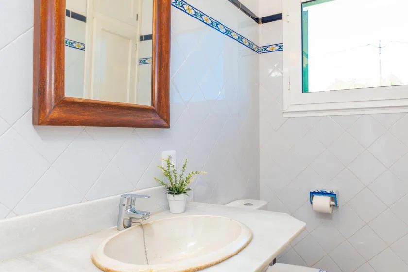 Un baño con azulejos y un lavabo debajo de un espejo con marco de madera.