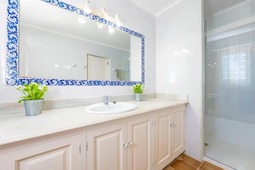 Un tocador de baño luminoso con un espejo amplio y una ducha de vidrio.