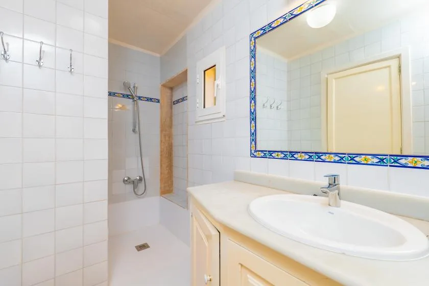 Un baño con azulejos, lavabo, espejo y ducha.