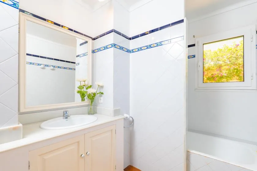 Un baño luminoso con lavabo, espejo y ventana.