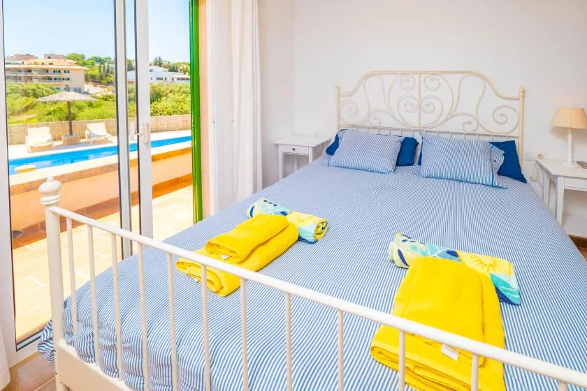 Un dormitorio con una cama grande, toallas dobladas y puertas de vidrio con vistas a una piscina.
