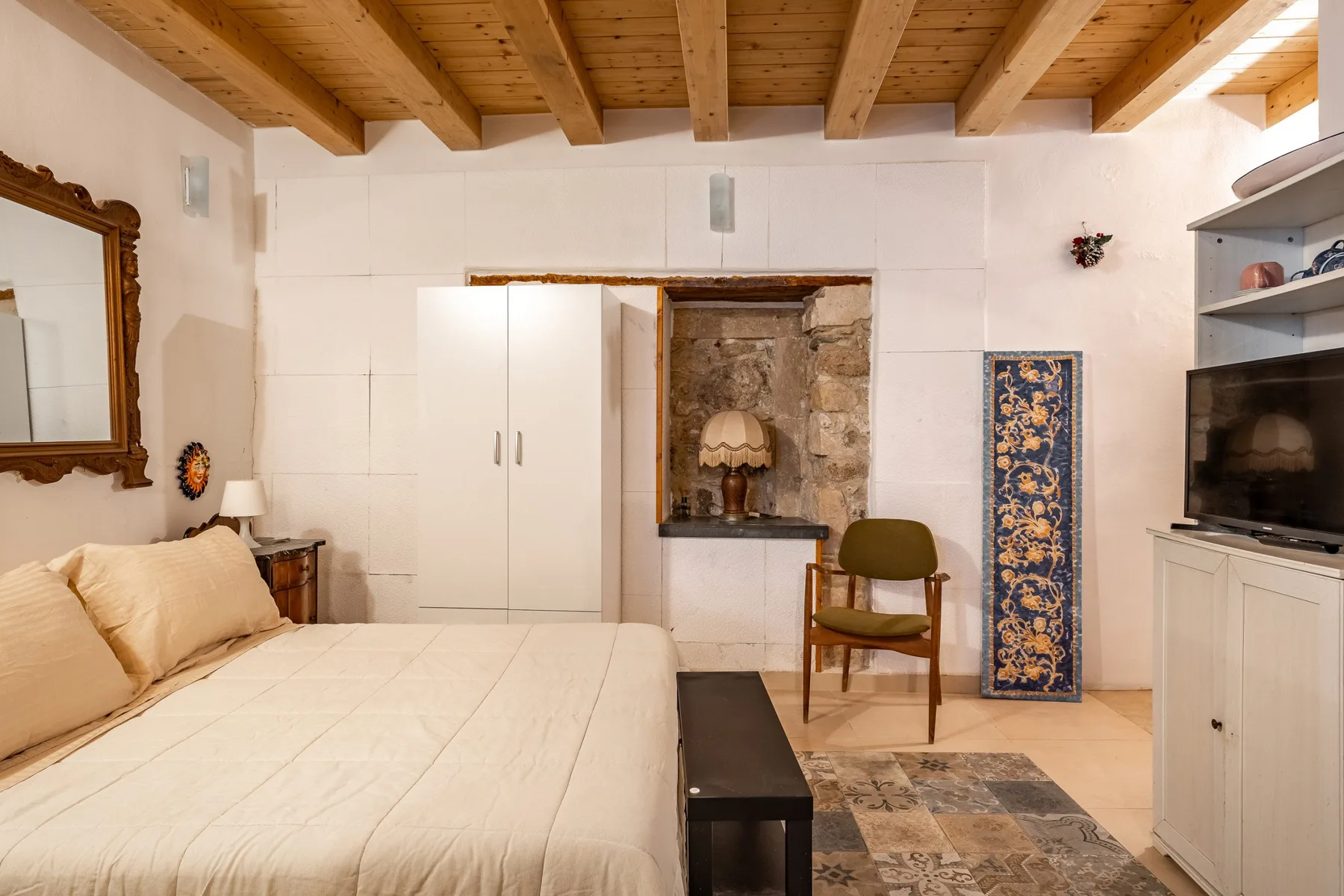 Un dormitorio con una cama, armarios empotrados y vigas de madera a la vista en el techo.