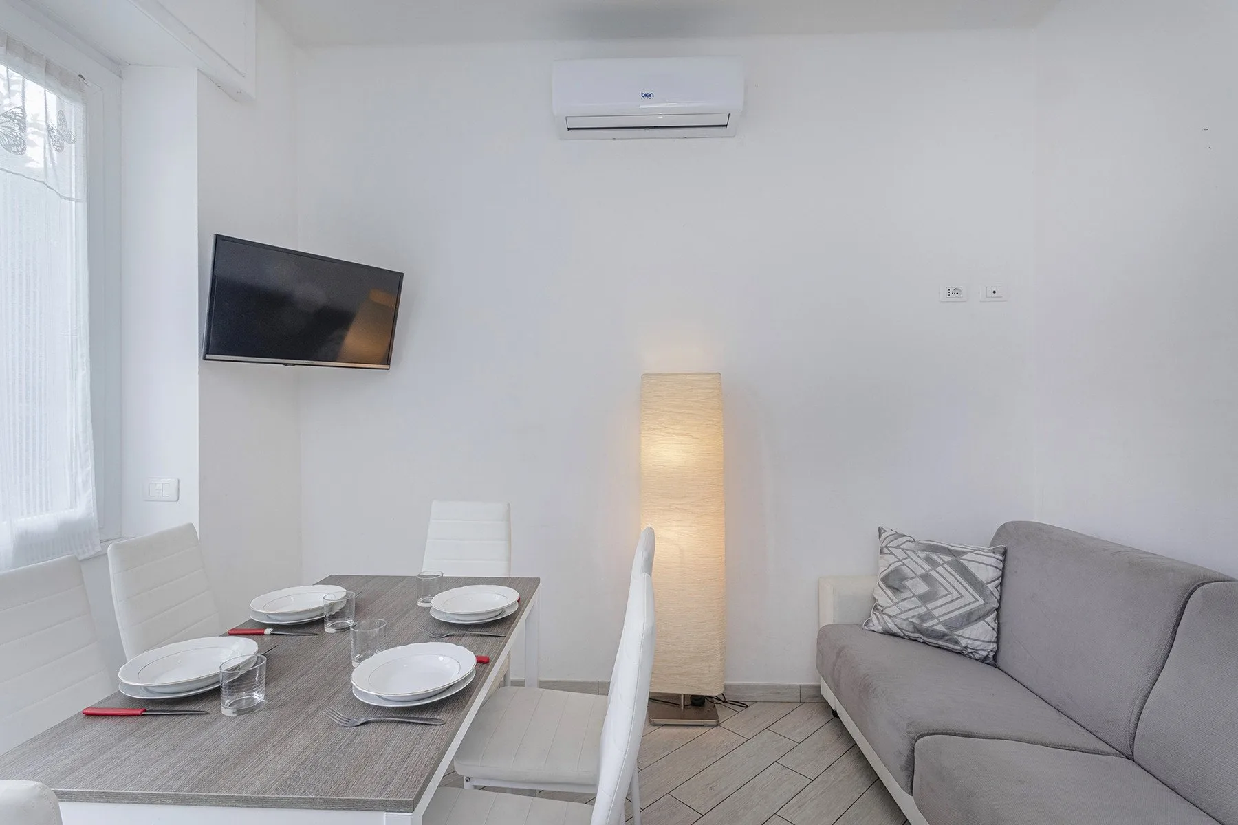 Una luminosa sala de estar y comedor con un sofá gris y una mesa de comedor.