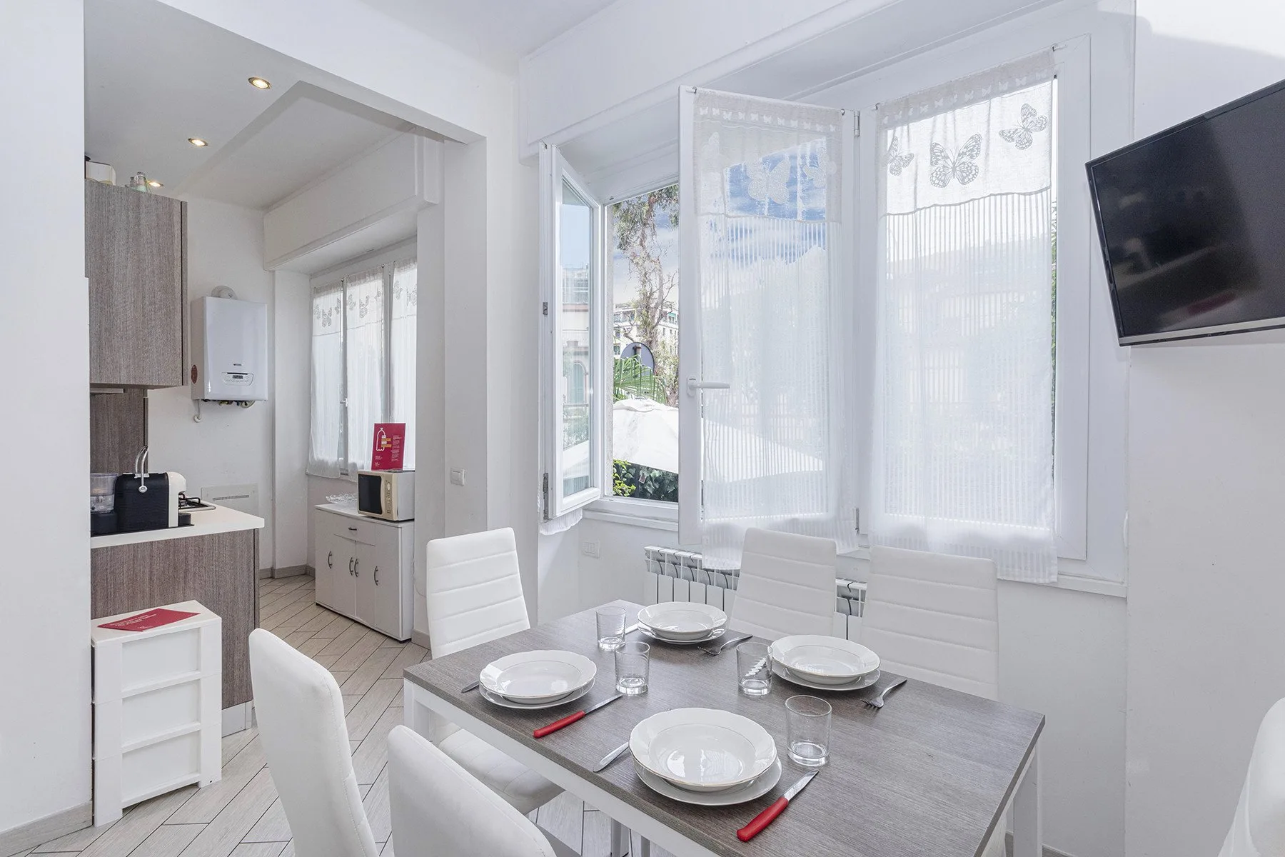 Un comedor luminoso con una mesa puesta junto a grandes ventanas.
