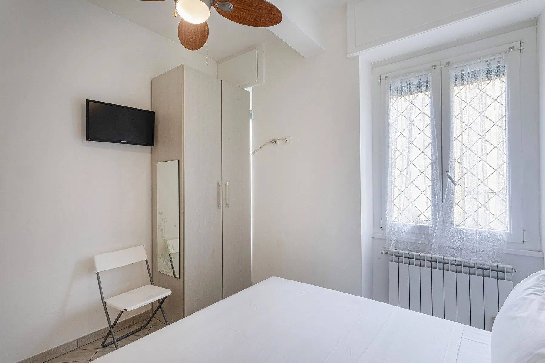 Un dormitorio luminoso con cama, armario y ventana.