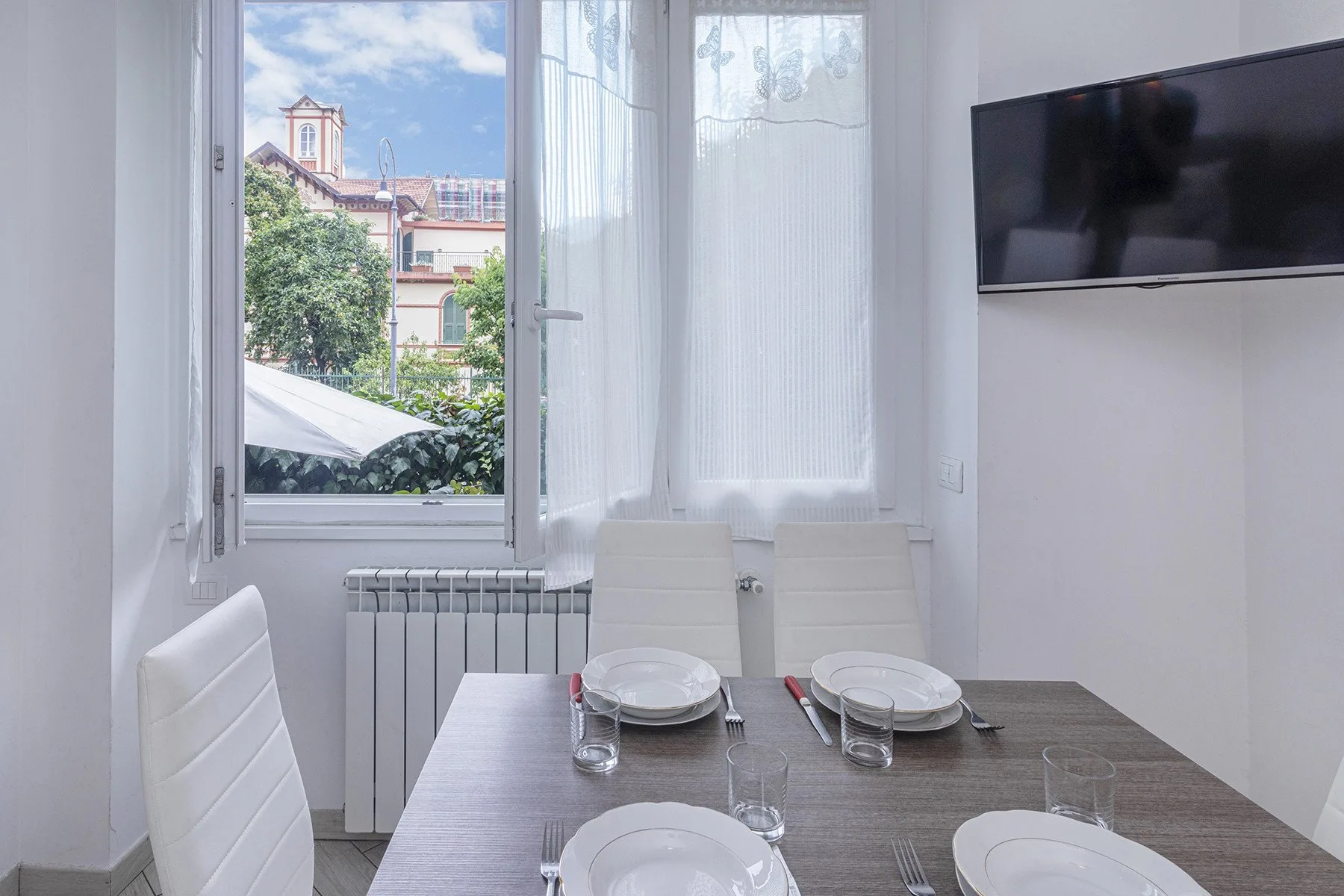 Comedor con una mesa preparada para comer junto a una ventana grande.