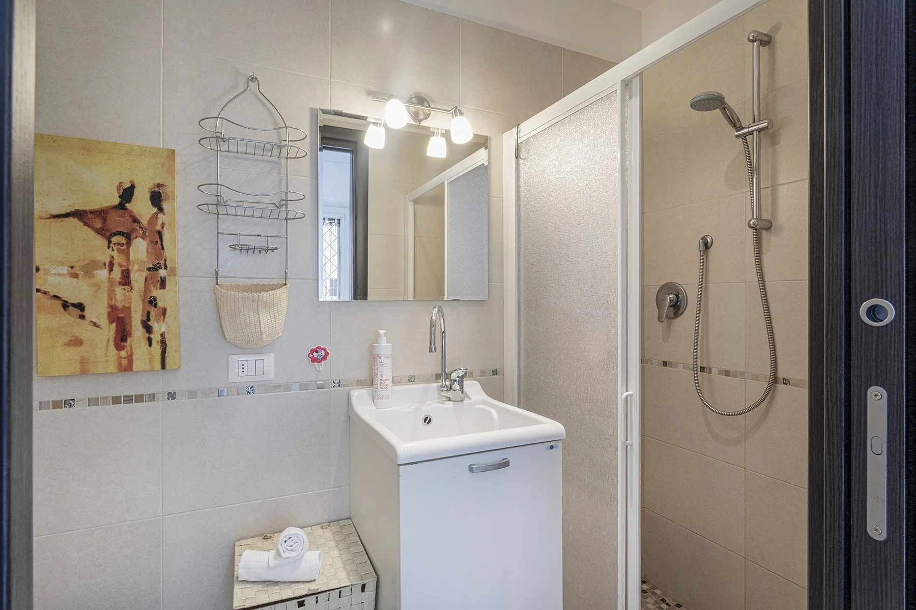 Un baño con lavabo, espejo y ducha con mampara de vidrio.