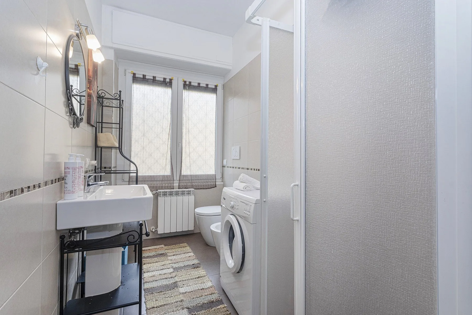 Un baño con lavabo, inodoro y lavadora junto a una ducha.