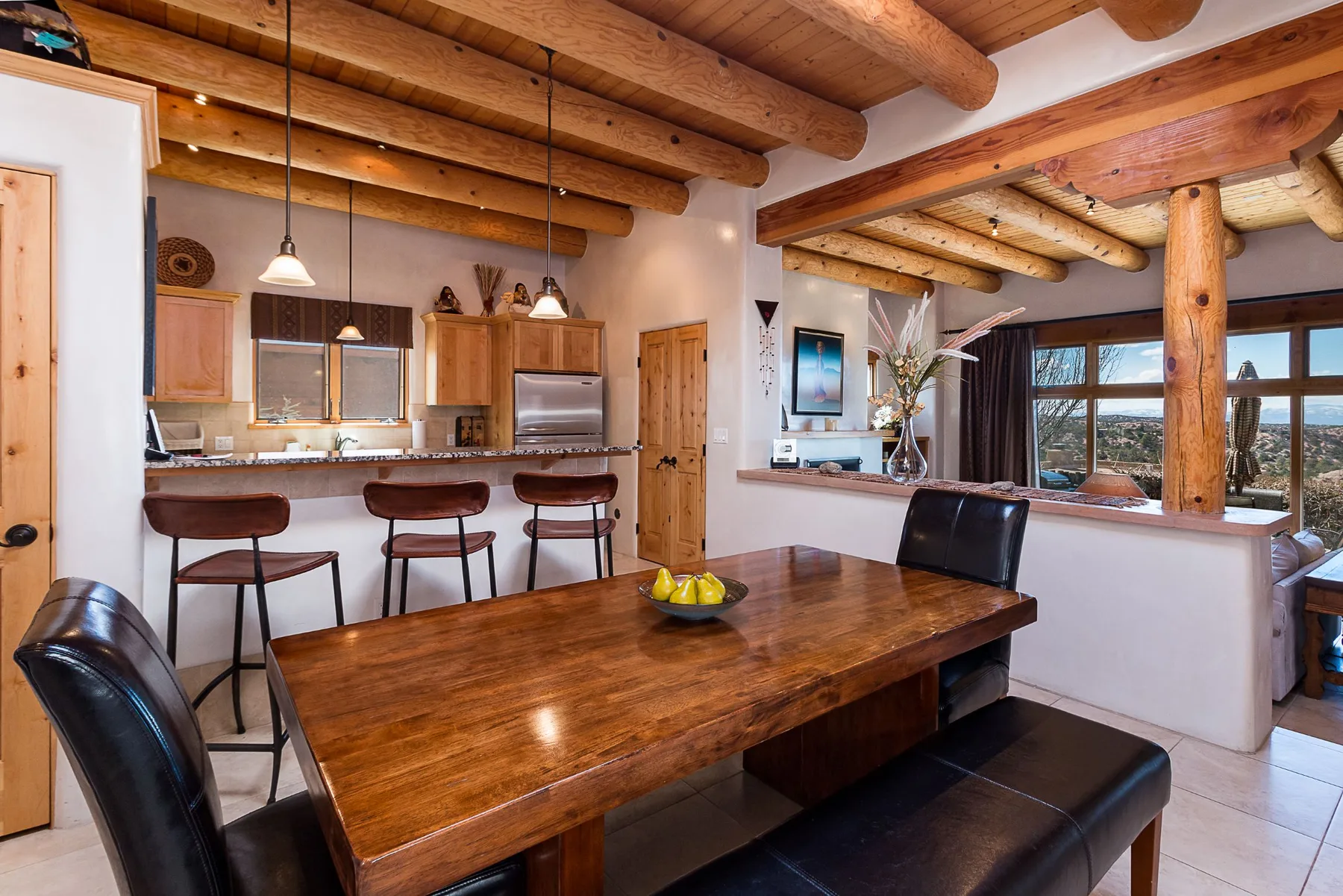 A dining area with a long wooden table beside an open kitchen.