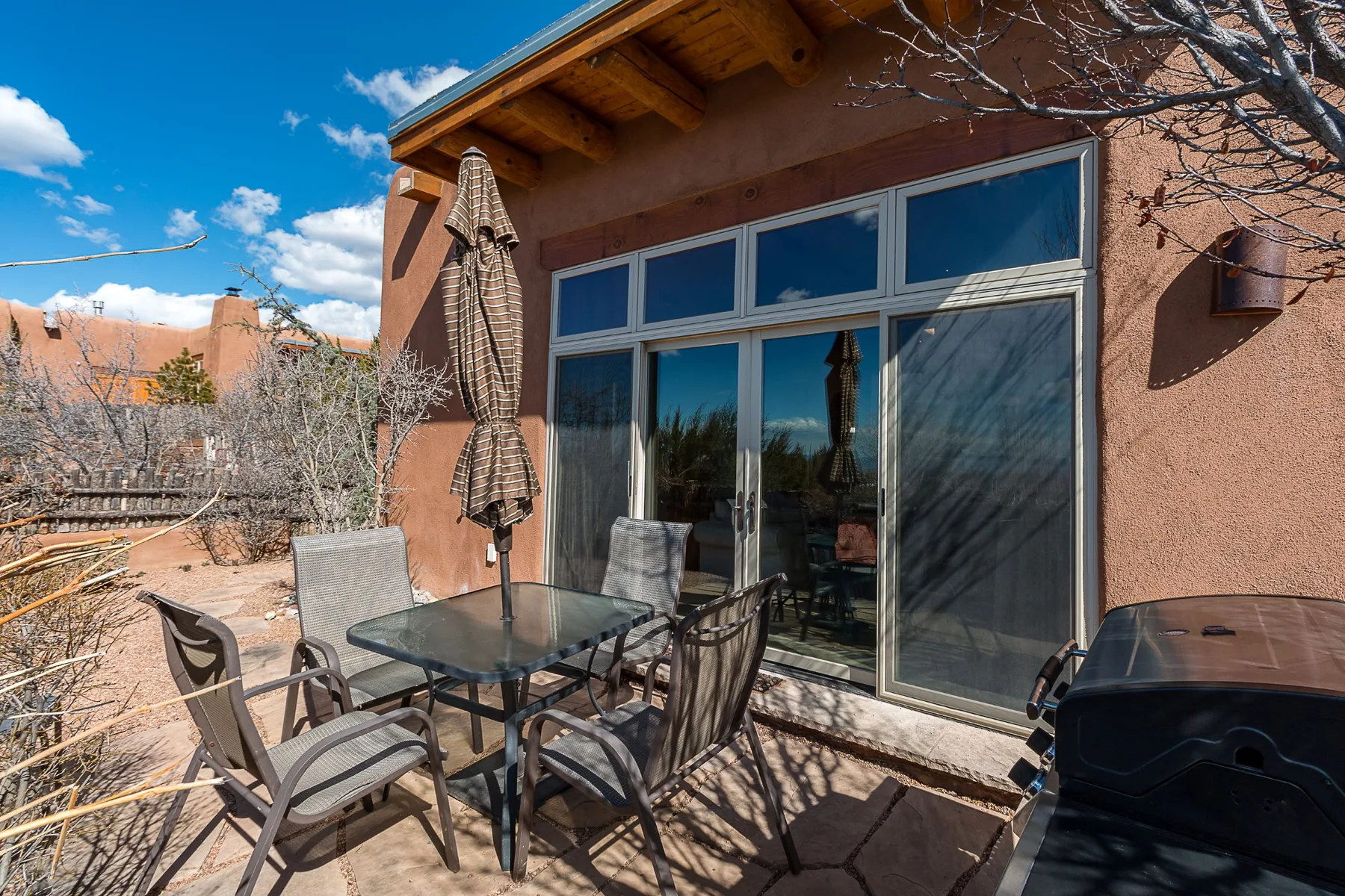 An outdoor patio with a glass-top table and sliding glass doors.