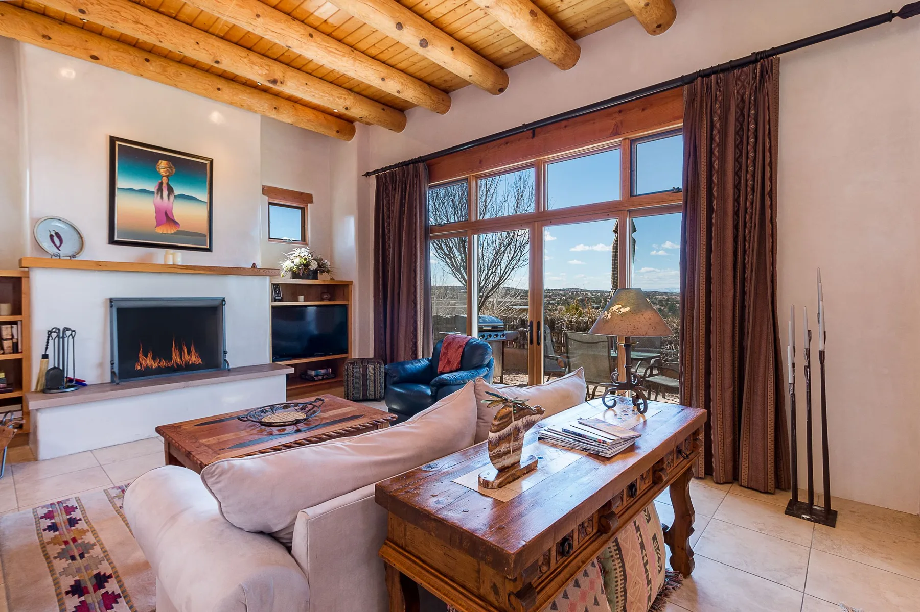A living room with seating, a fireplace, and large windows overlooking the outdoors.