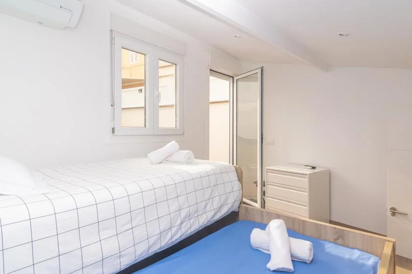 Un dormitorio luminoso con una cama bien tendida y una ventana.