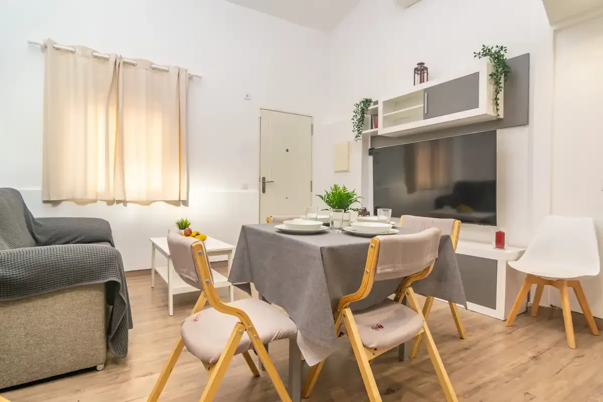 Una sala de estar y comedor con televisor, mesa y asientos.