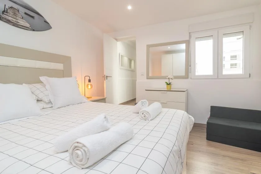 Un dormitorio luminoso con una cama bien hecha y una ventana.