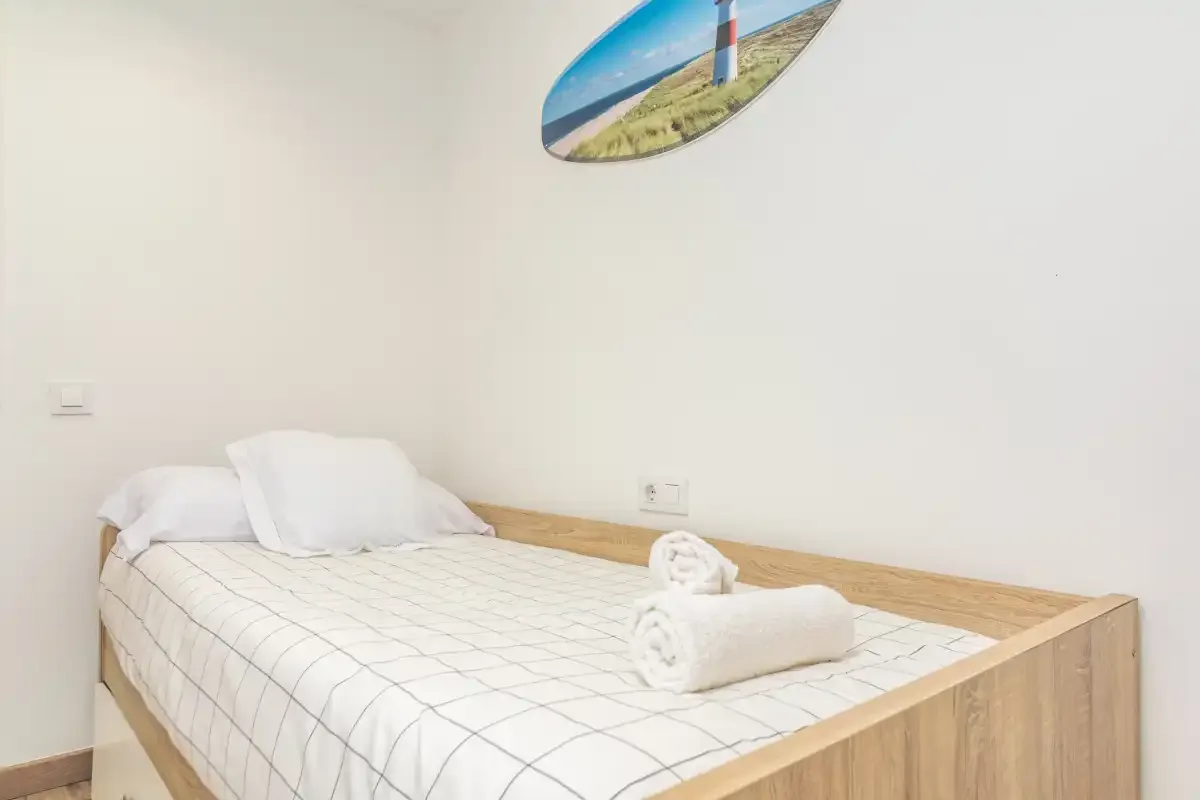 Un dormitorio con una cama bien arreglada y toallas dobladas.
