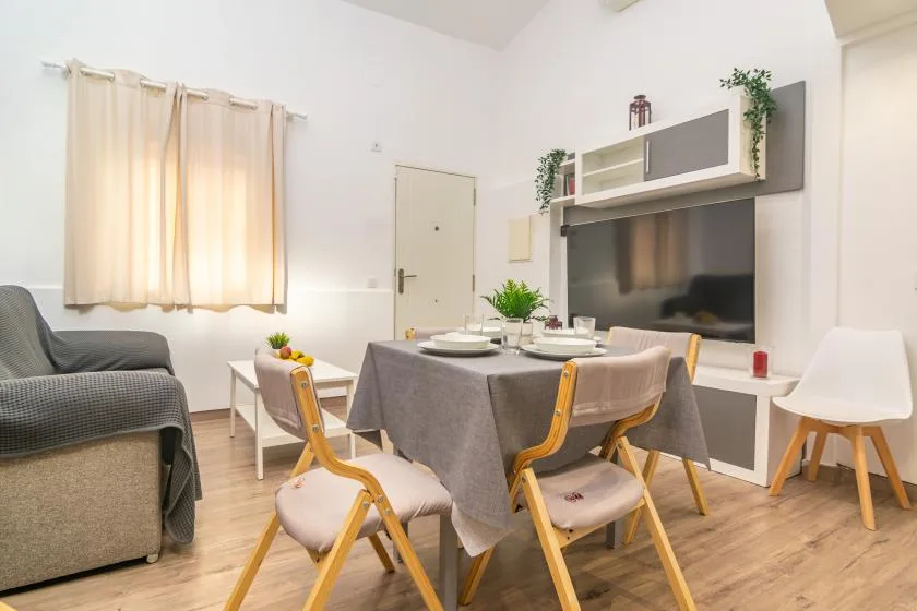 Un comedor con una mesa y sillas frente a un televisor.