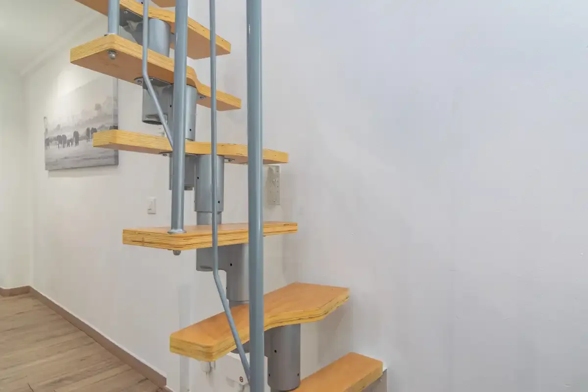 Una escalera moderna con peldaños de madera y soportes metálicos.