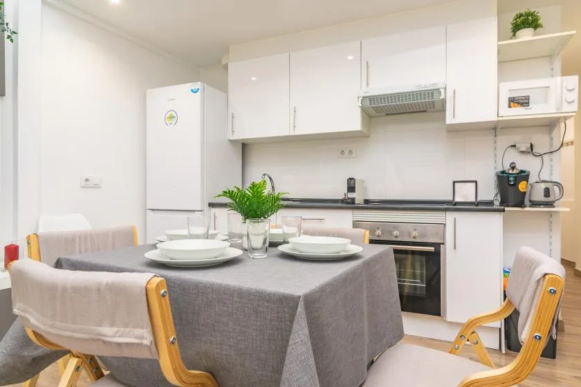 Una mesa puesta está en una cocina luminosa con armarios blancos.