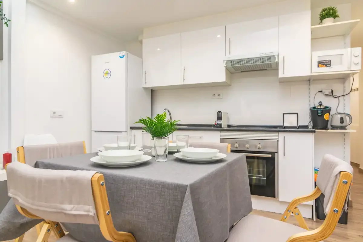 Comedor con una mesa puesta frente a una cocina compacta.
