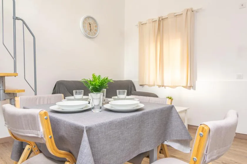 Un comedor con la mesa puesta y una planta en maceta.