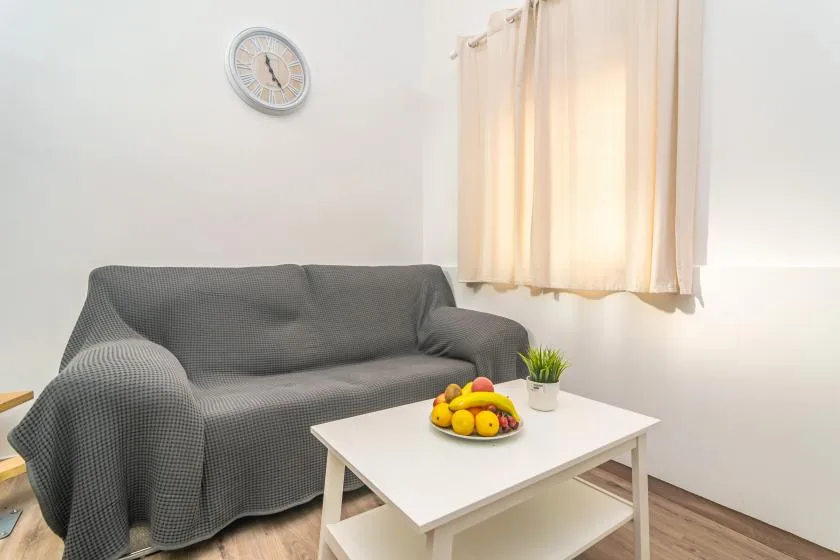 A living room with a gray sofa, a white coffee table, and fruit.