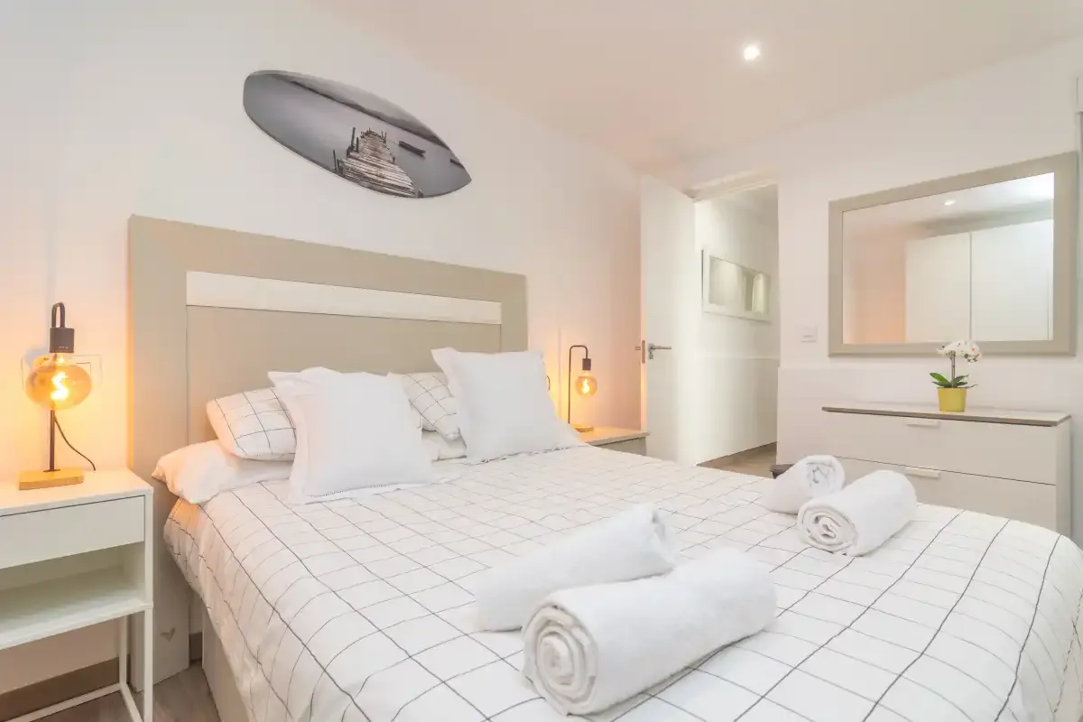 Un dormitorio luminoso con una cama bien hecha y toallas dobladas.