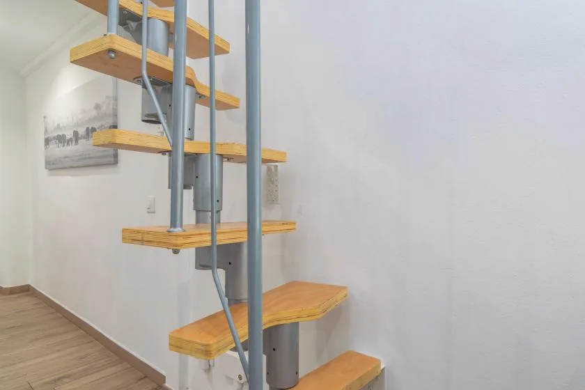Una escalera interior con peldaños de madera y soportes metálicos.