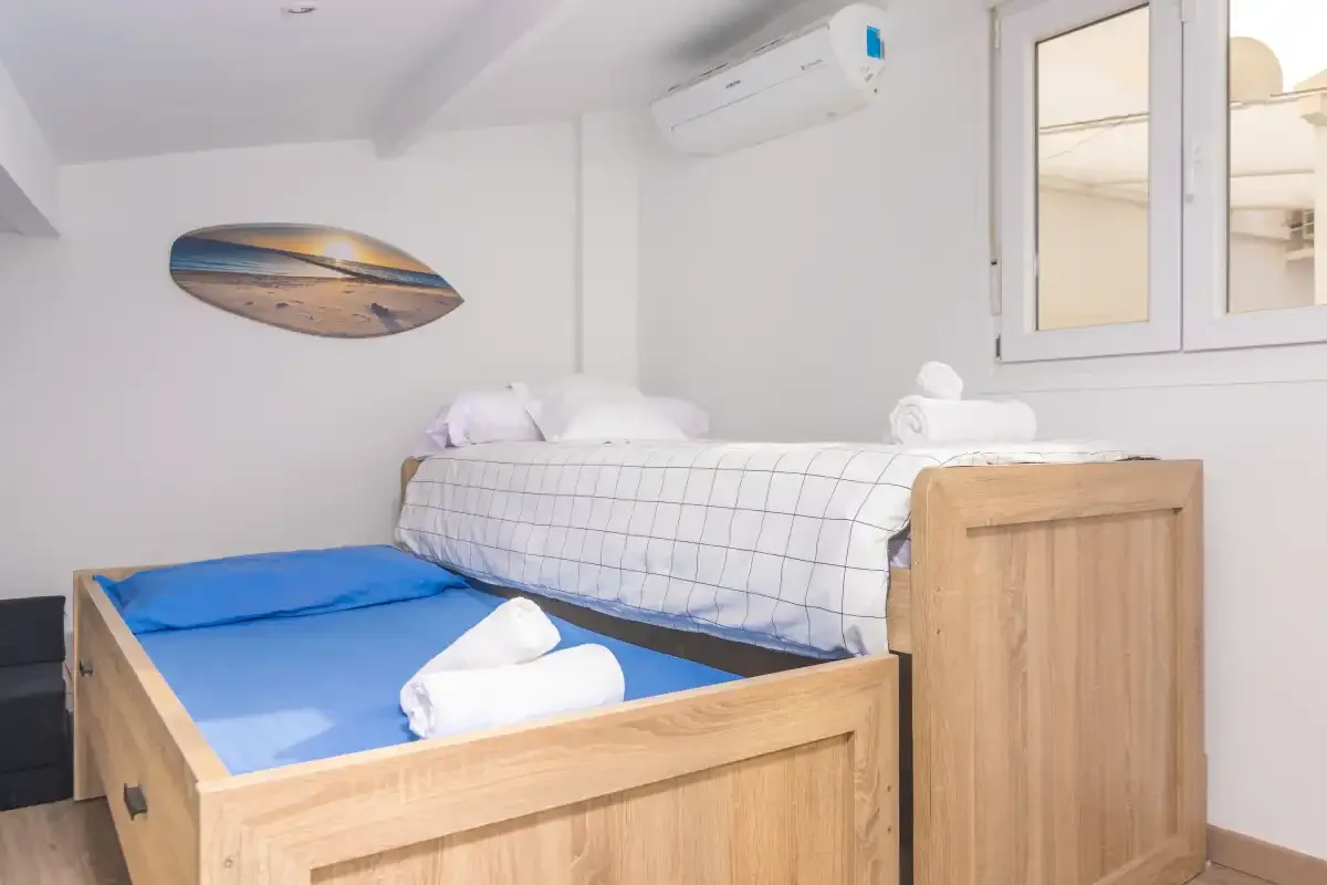 Un dormitorio con dos camas, ropa de cama blanca y aire acondicionado.