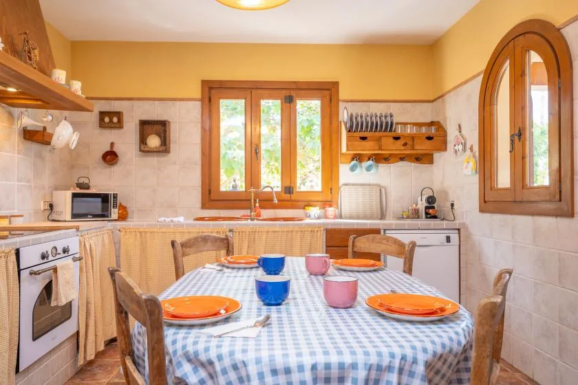 A warm-toned kitchen and dining area with a set table beside the windows.