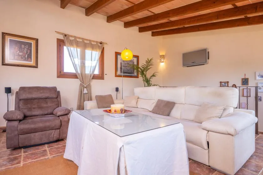 A living room with a white sofa, a recliner, and a glass-topped table.