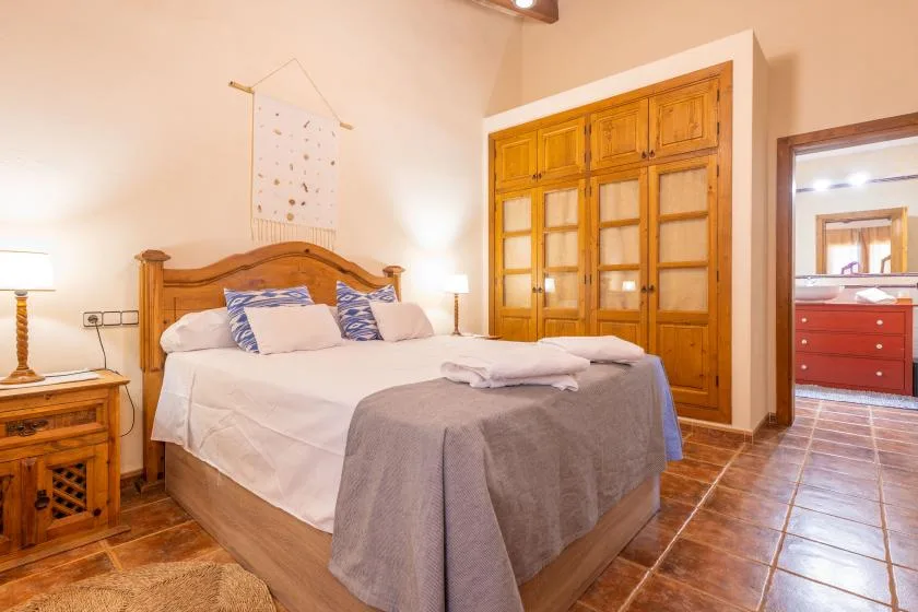 A bedroom with a wooden bed, neatly arranged pillows, and a folded blanket.