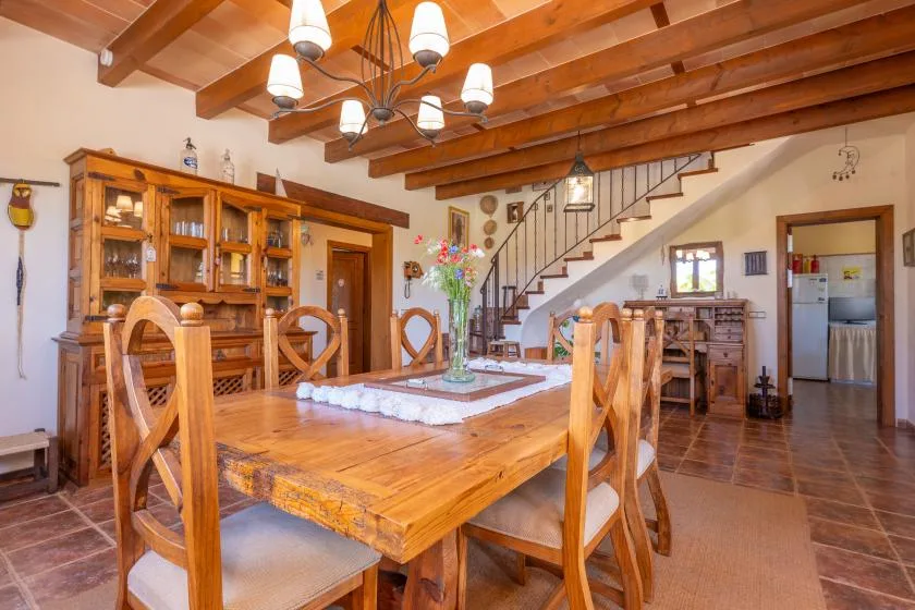 A dining room with a large wooden table beneath exposed ceiling beams.