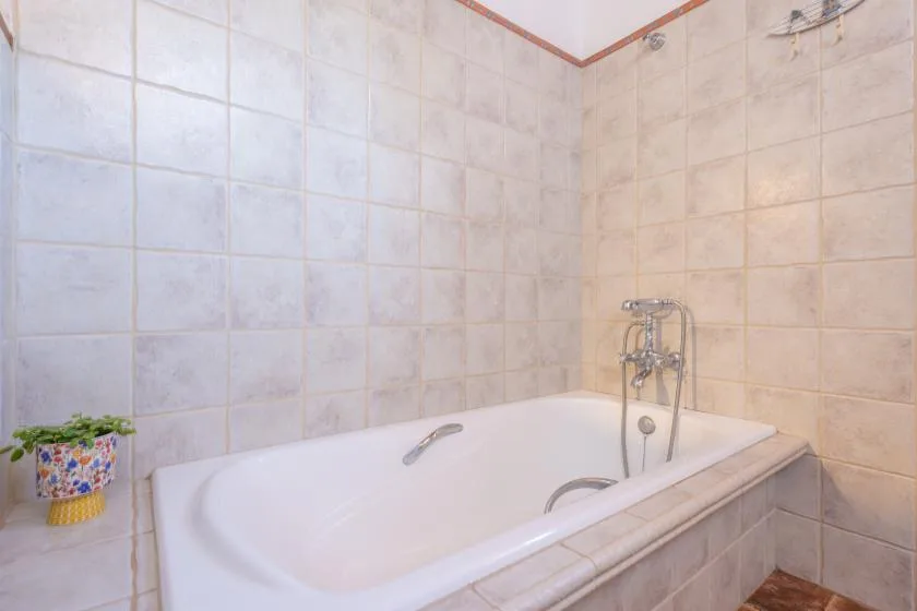 A tiled bathroom with a bathtub and wall-mounted shower fixture.