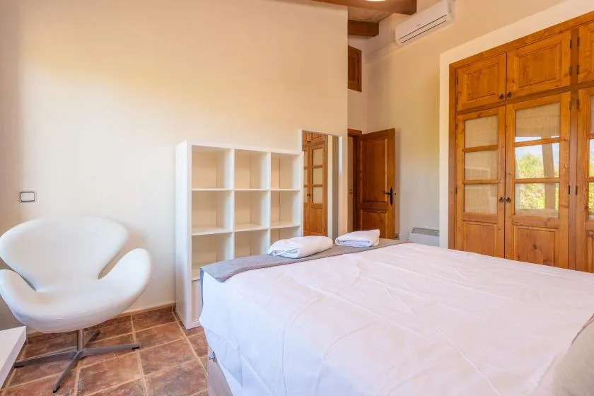 A bedroom with a bed, white shelving, and wooden doors.