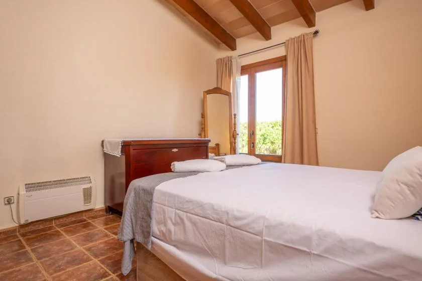A bright bedroom with a large bed and a window with curtains.