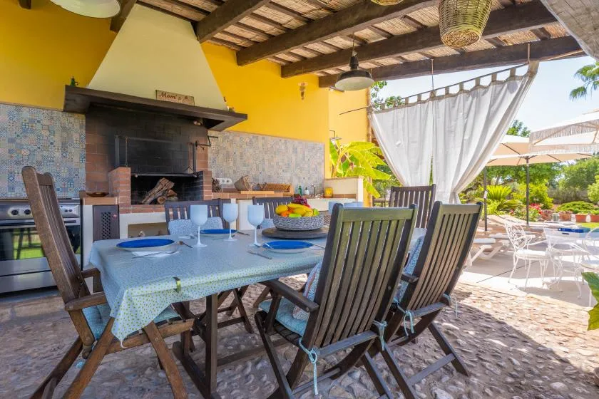 A covered outdoor dining area with a set table beside a built-in grill.