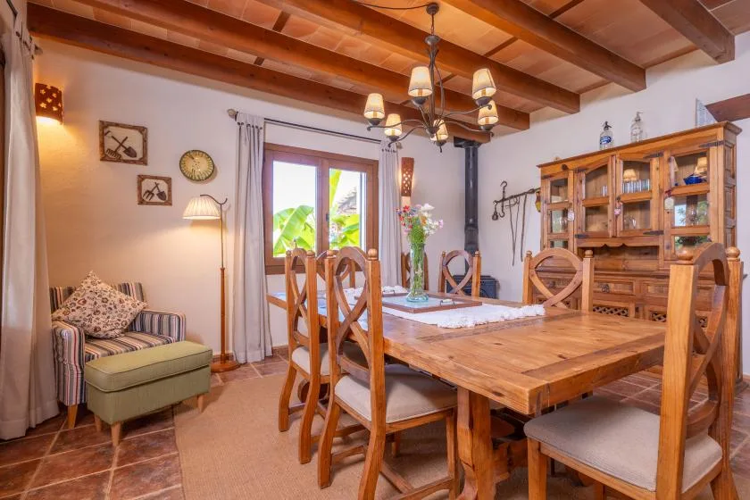 A dining room with a large wooden table, chairs, and a cabinet.